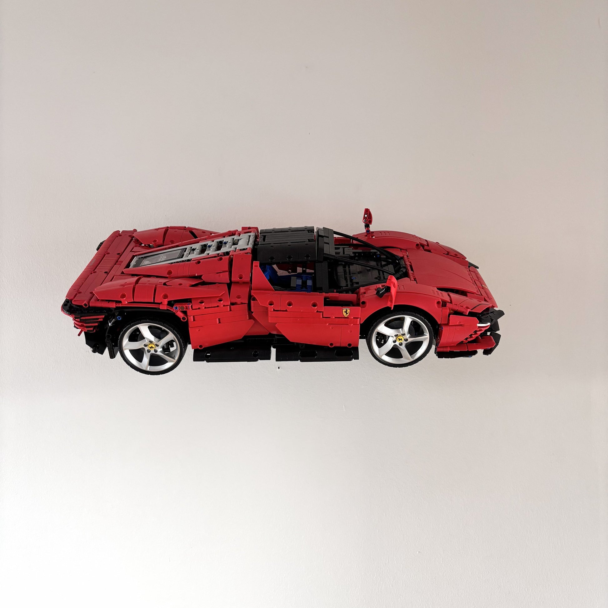 Horisontal væg-holder til LEGO® 42143 Ferrari monteret på væg i 30 graders udstilling
