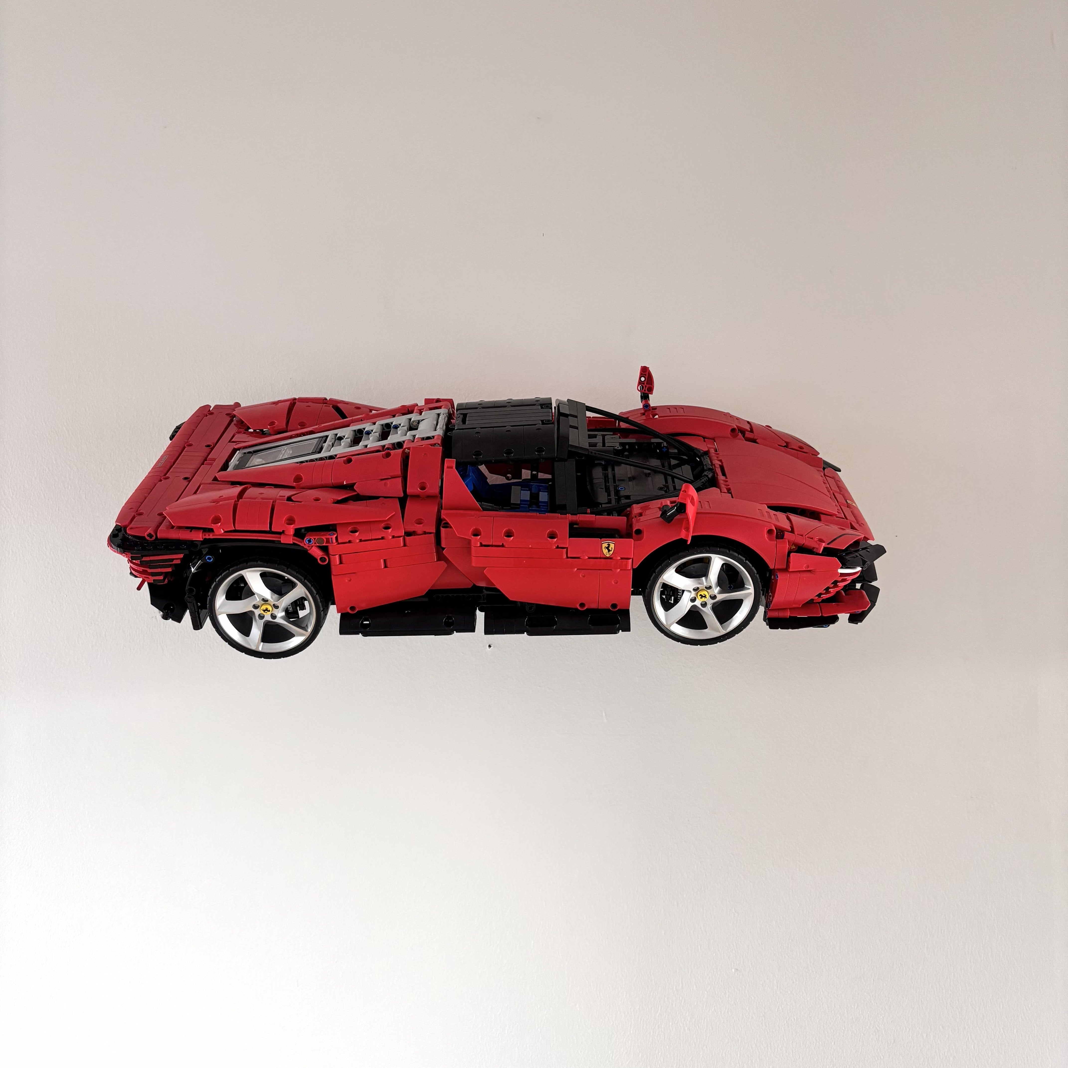 Horisontal væg-holder til LEGO® 42143 Ferrari monteret på væg i 30 graders udstilling